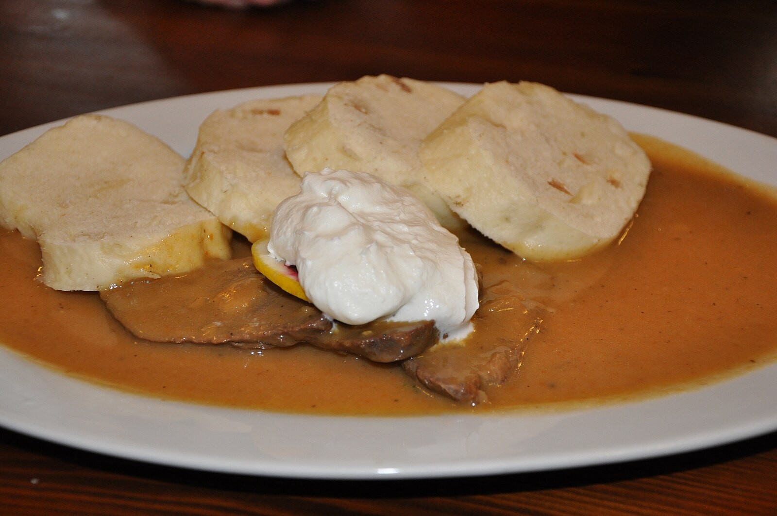 Plate of svíčková with several clearly visible slices of Czech bread dumpling.