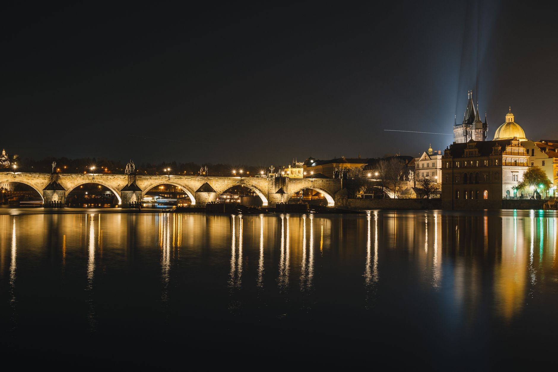 Charles Bridge and Prague skyline illuminated after dark.