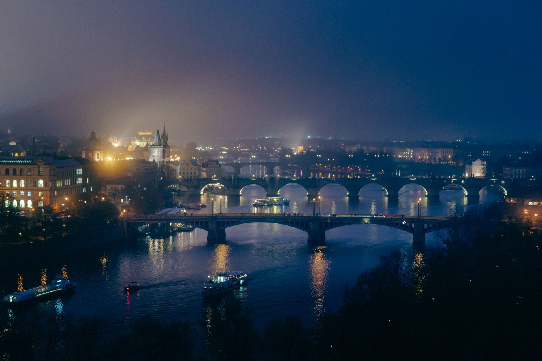 Illuminated Prague riverfront and bridges after dark.