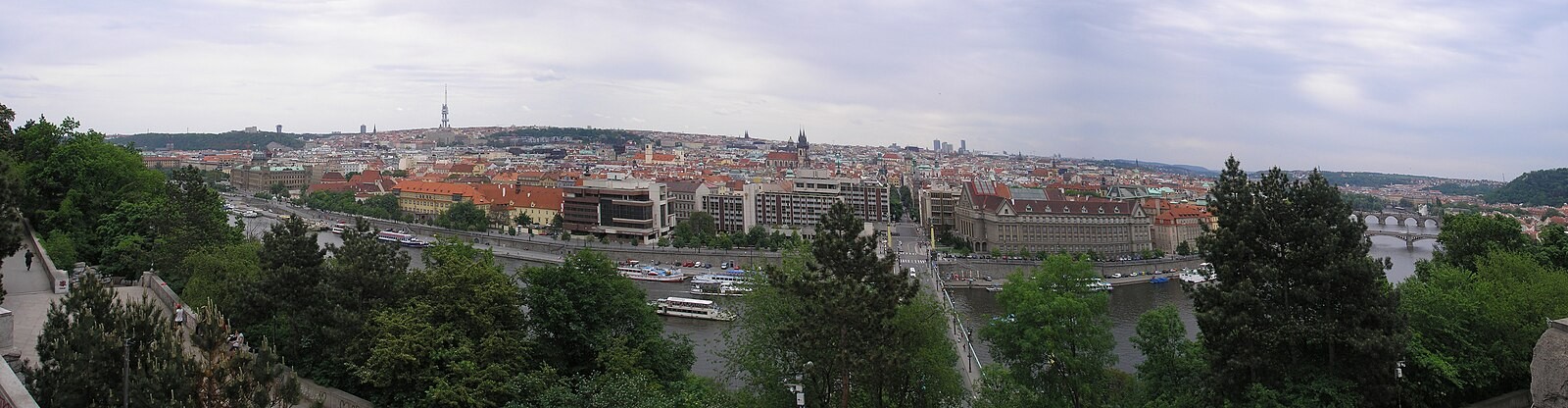 Broad Prague and Vltava panorama viewed from Letná with public green space in the foreground.