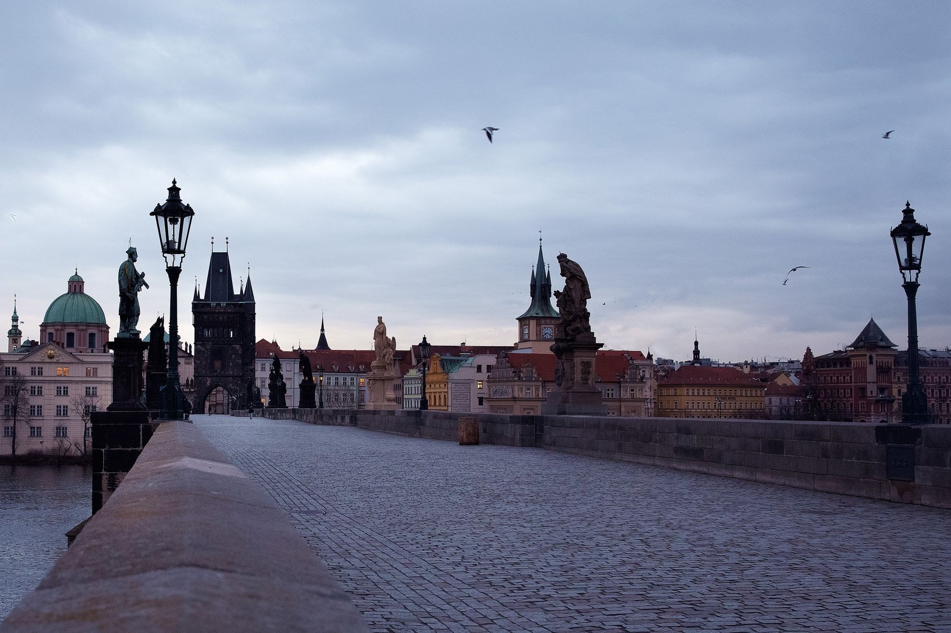 Charles Bridge under heavy grey cloud and wet-weather atmosphere.