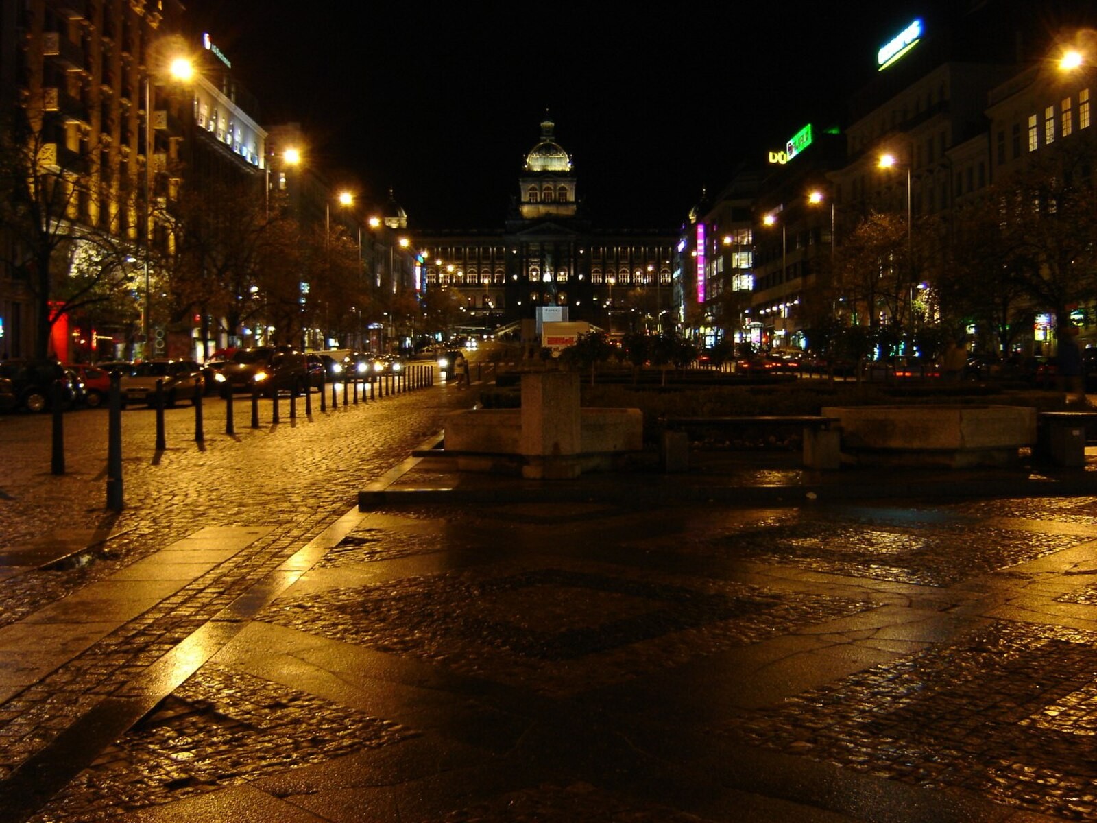 Upper Wenceslas Square at night with lit buildings, traffic and street activity.