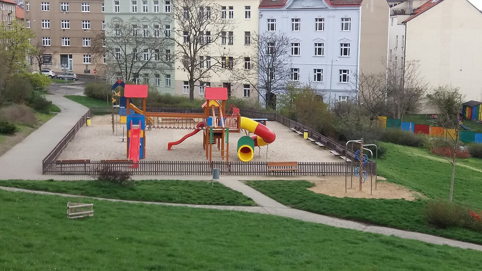 Prague neighbourhood playground with slides and climbing/play equipment; no children or identifiable people are visible.