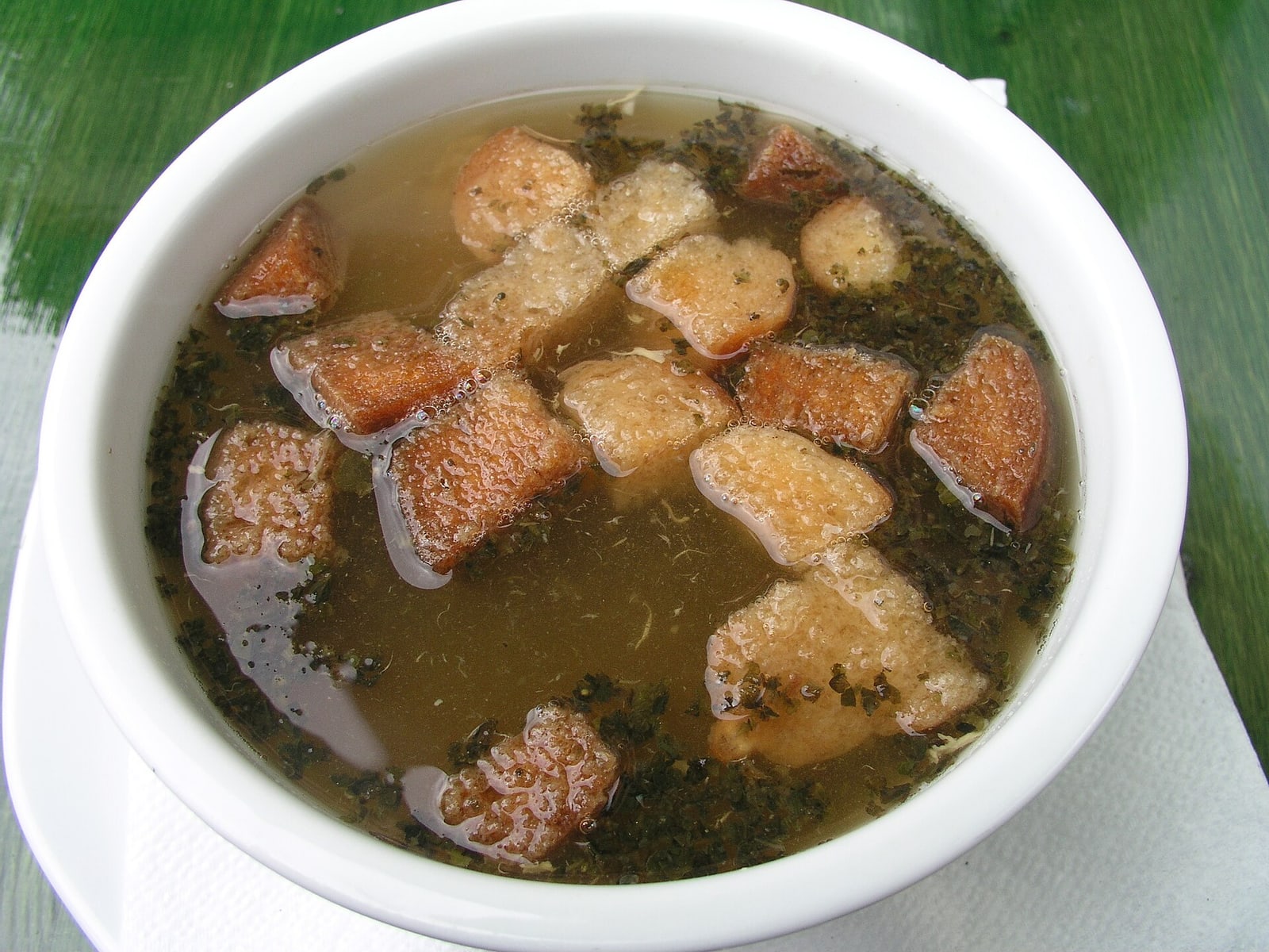 A materially different bowl of Czech česnečka with visible potato/cheese/crouton components.