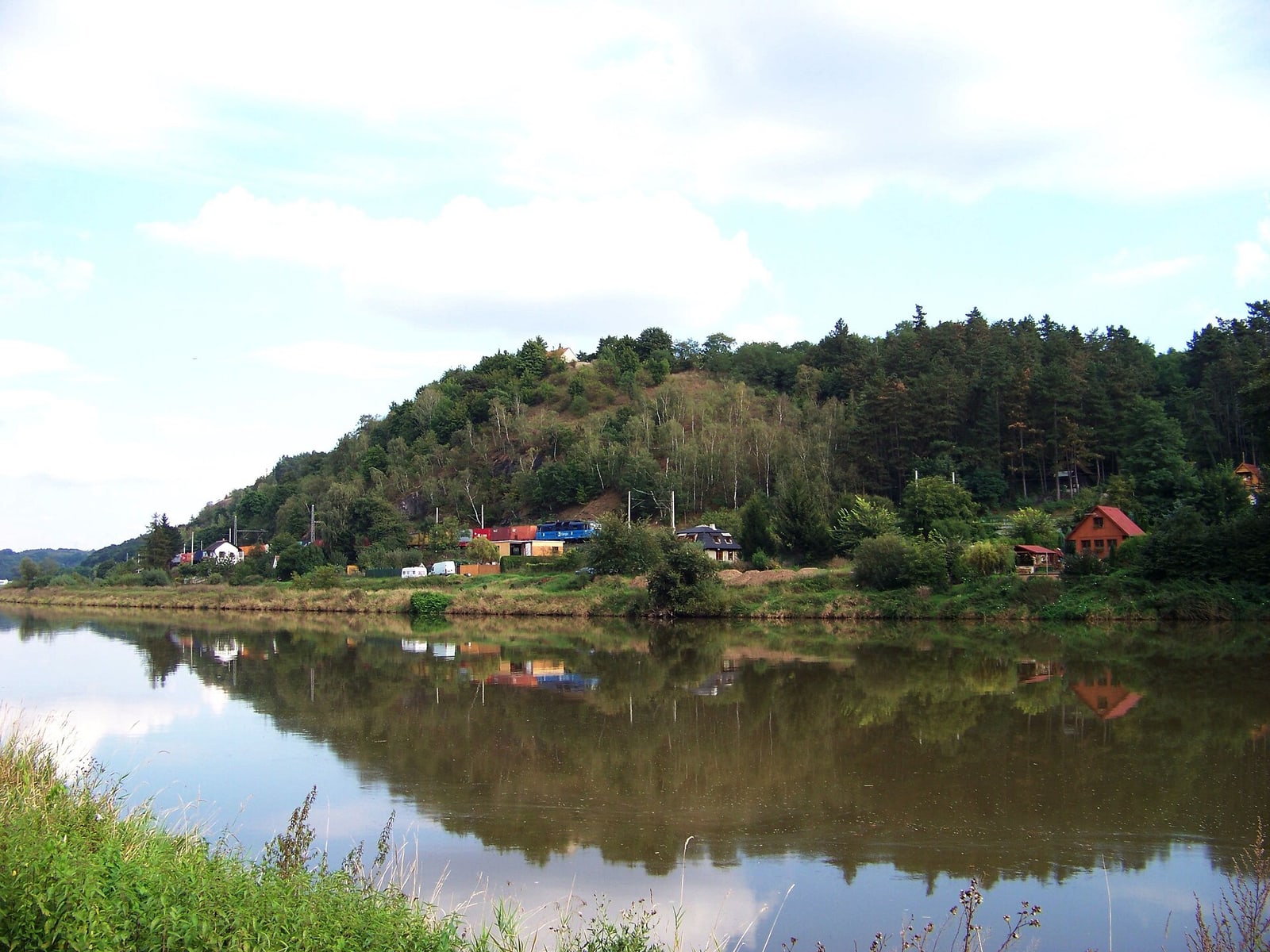 Wider landscape view of Levý Hradec across the Vltava, showing its strategic setting.