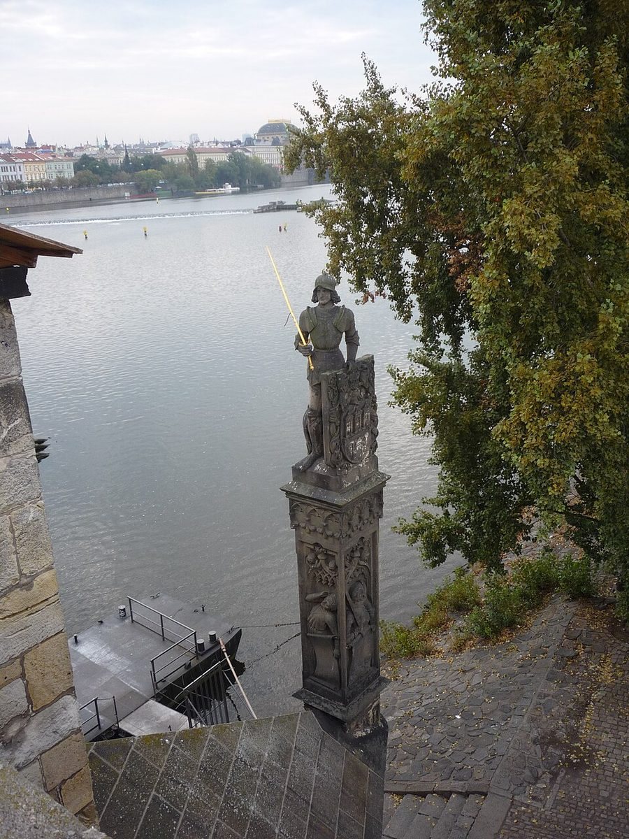 Portrait view of the carved column and Bruncvík figure beside the Vltava.
