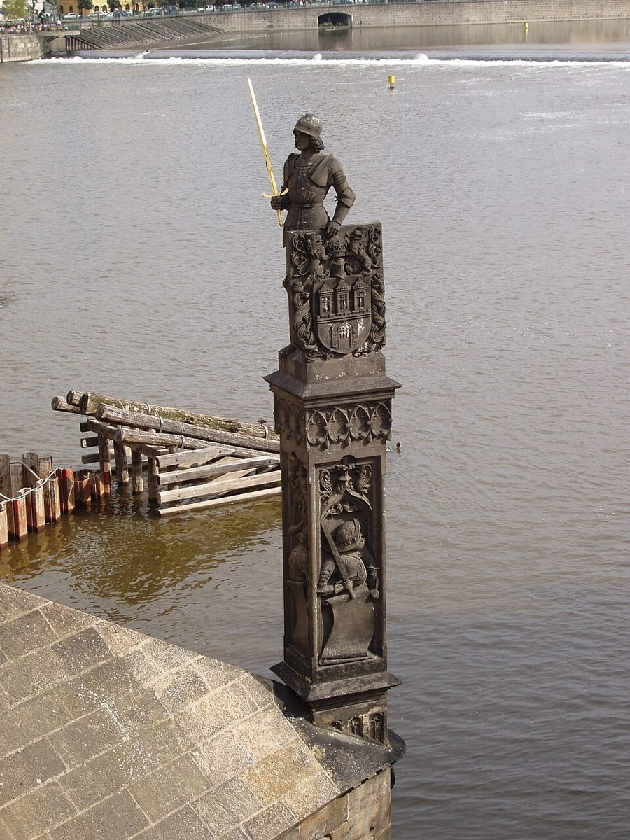 Clean full-height view of the carved column and figure against the river.