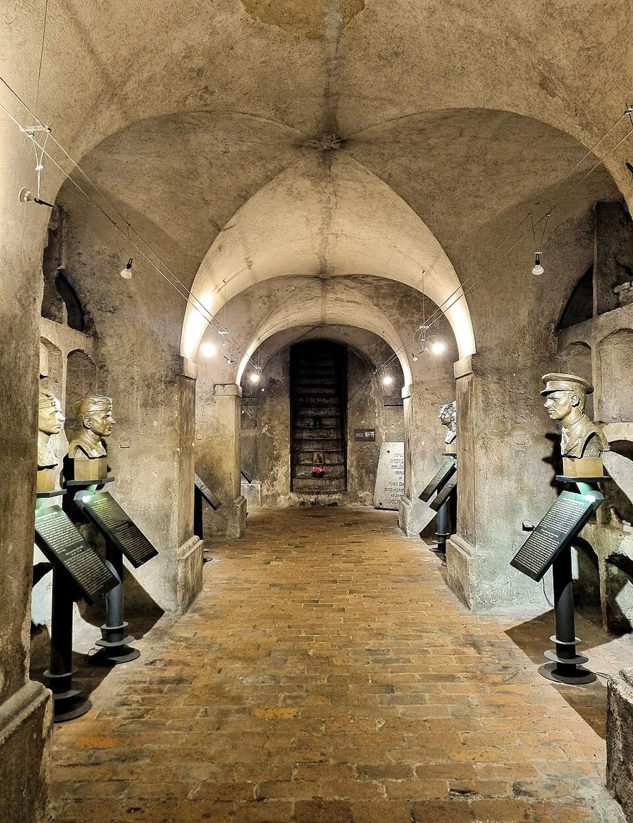 Long portrait down the authentic crypt interior with brick floor, stone vaults and memorial busts.