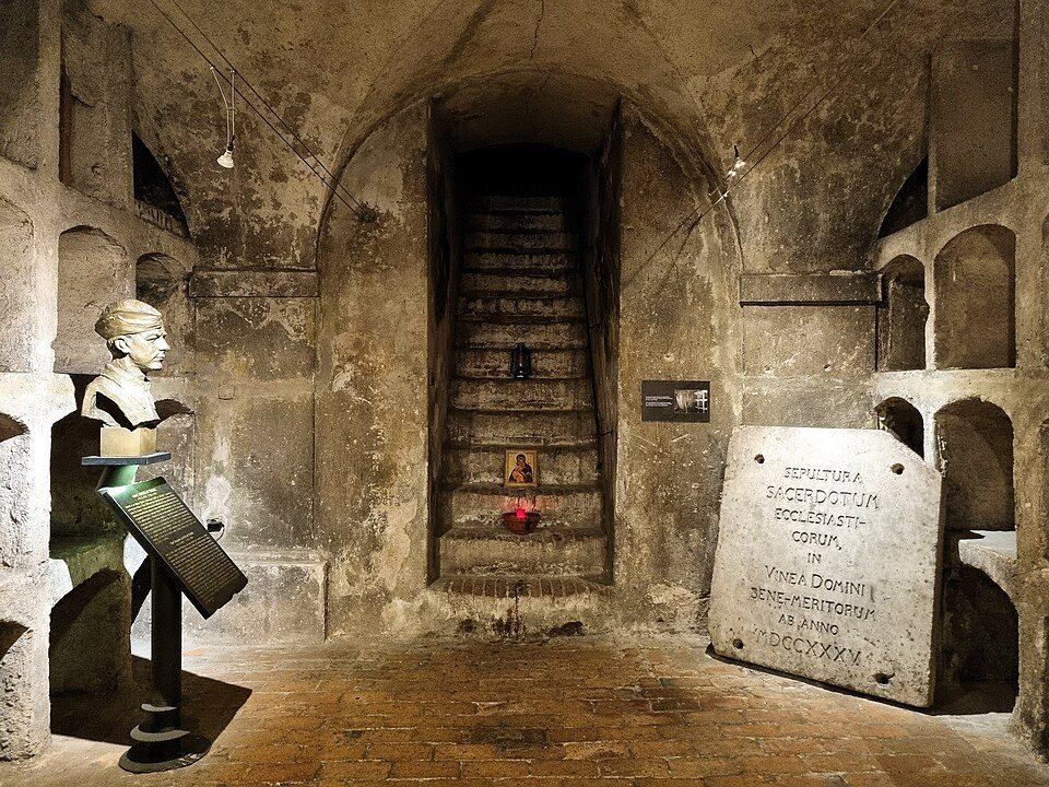 Historic crypt wall with stair/doorway, bust and memorial stone.
