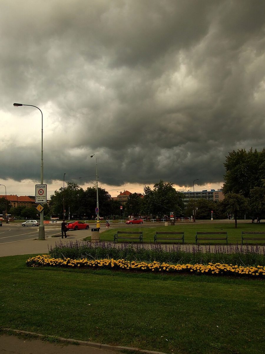 Broad circular/green expanse of Victory Square under dramatic storm clouds.