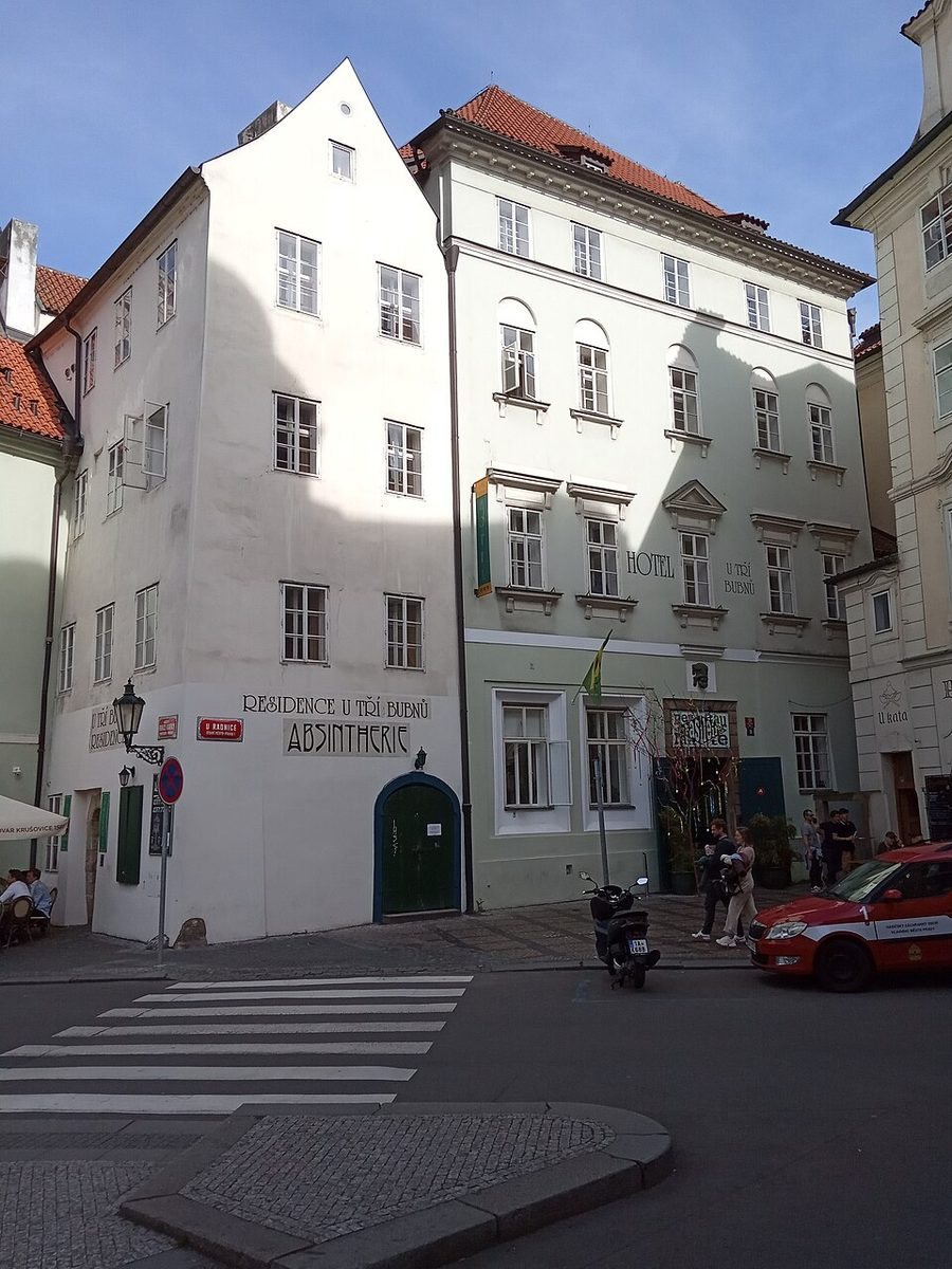 Clean portrait of the white corner Kafka-house building from across the junction.