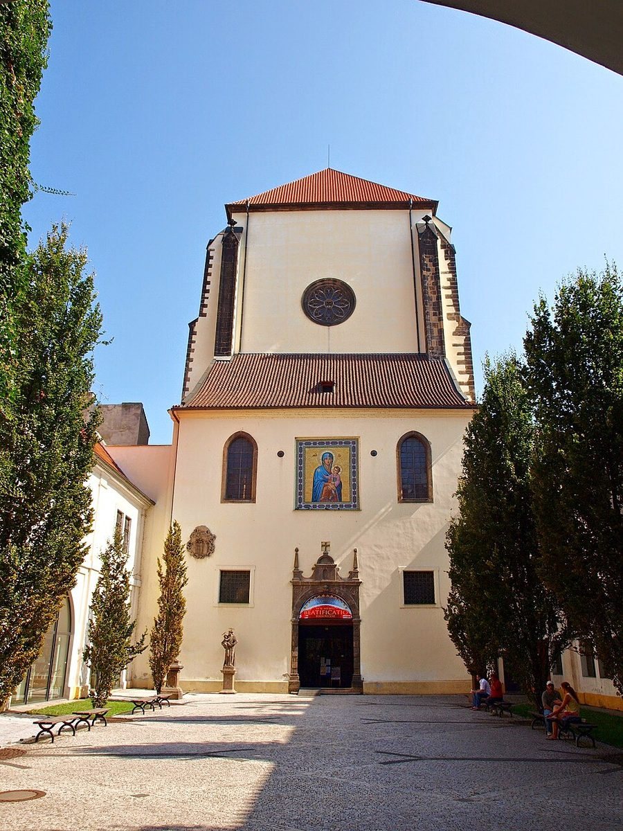 Centered church façade seen through the courtyard, with strong blue sky.