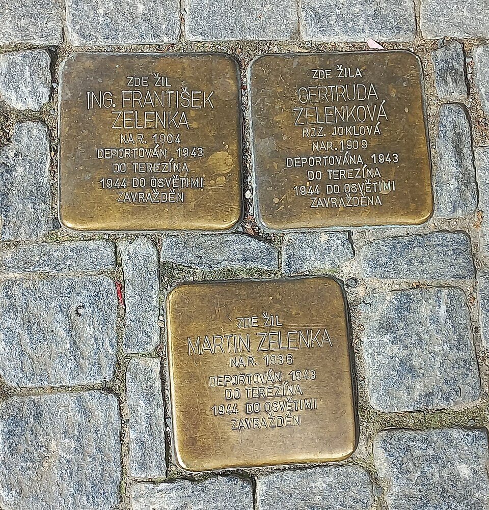 Three brass Stolpersteine set flush into cobblestones, inscriptions clearly visible.