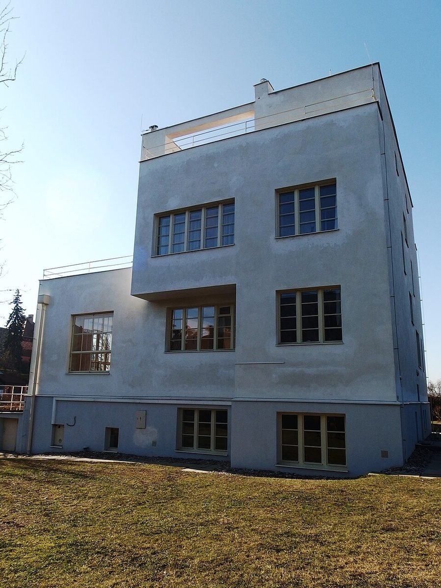 Clean frontal view of a white modernist villa with flat roof and rectangular windows.