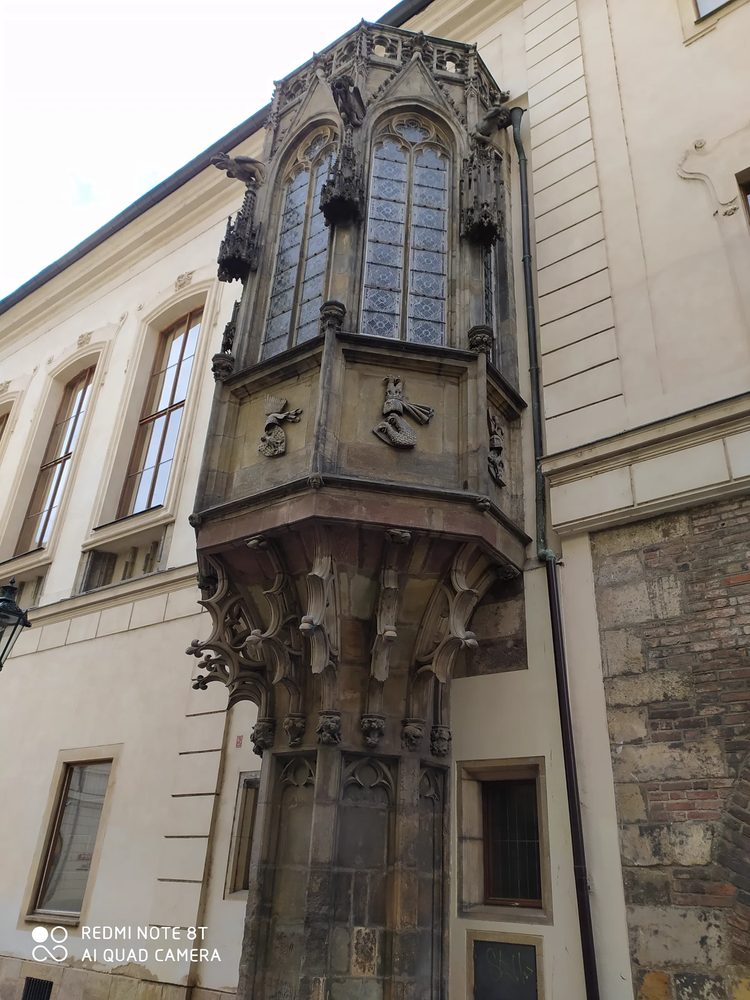 Approved close architectural view of a tall historic Prague building with steep roof/gable and detailed facade.