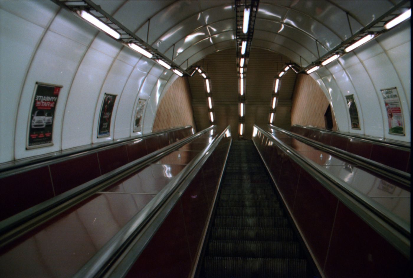 Empty Prague metro escalator is visibly framed in a strong symmetrical tunnel composition.
