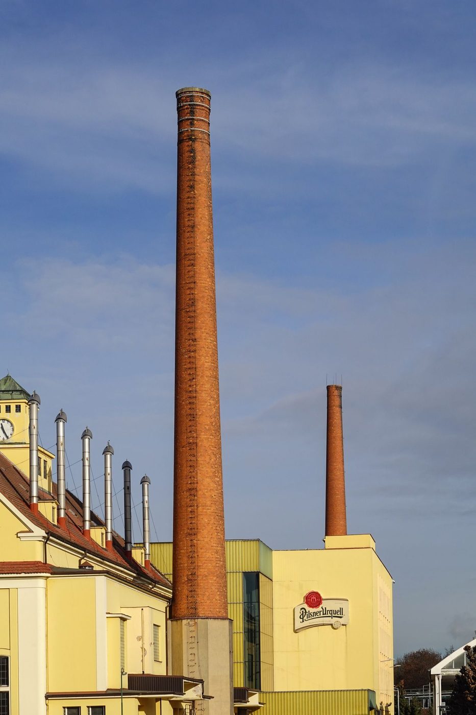 Tall historic brewery chimneys/buildings are visibly identified as Pilsner Urquell Brewery in Pilsen.