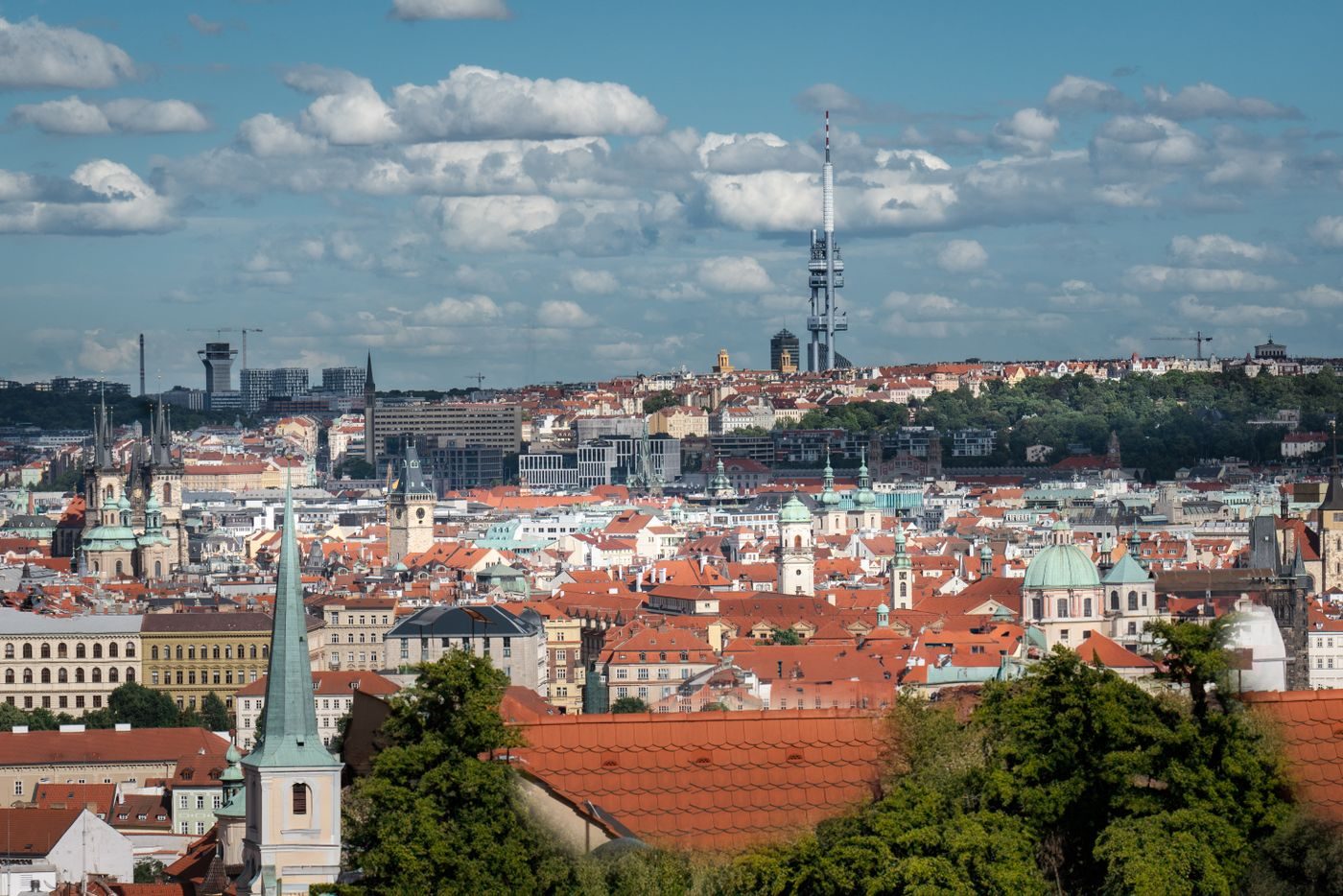 Dense Prague rooftops with Žižkov Television Tower visibly rising on the skyline provide eastern-city context near the Vítkov/Žižkov landscape.