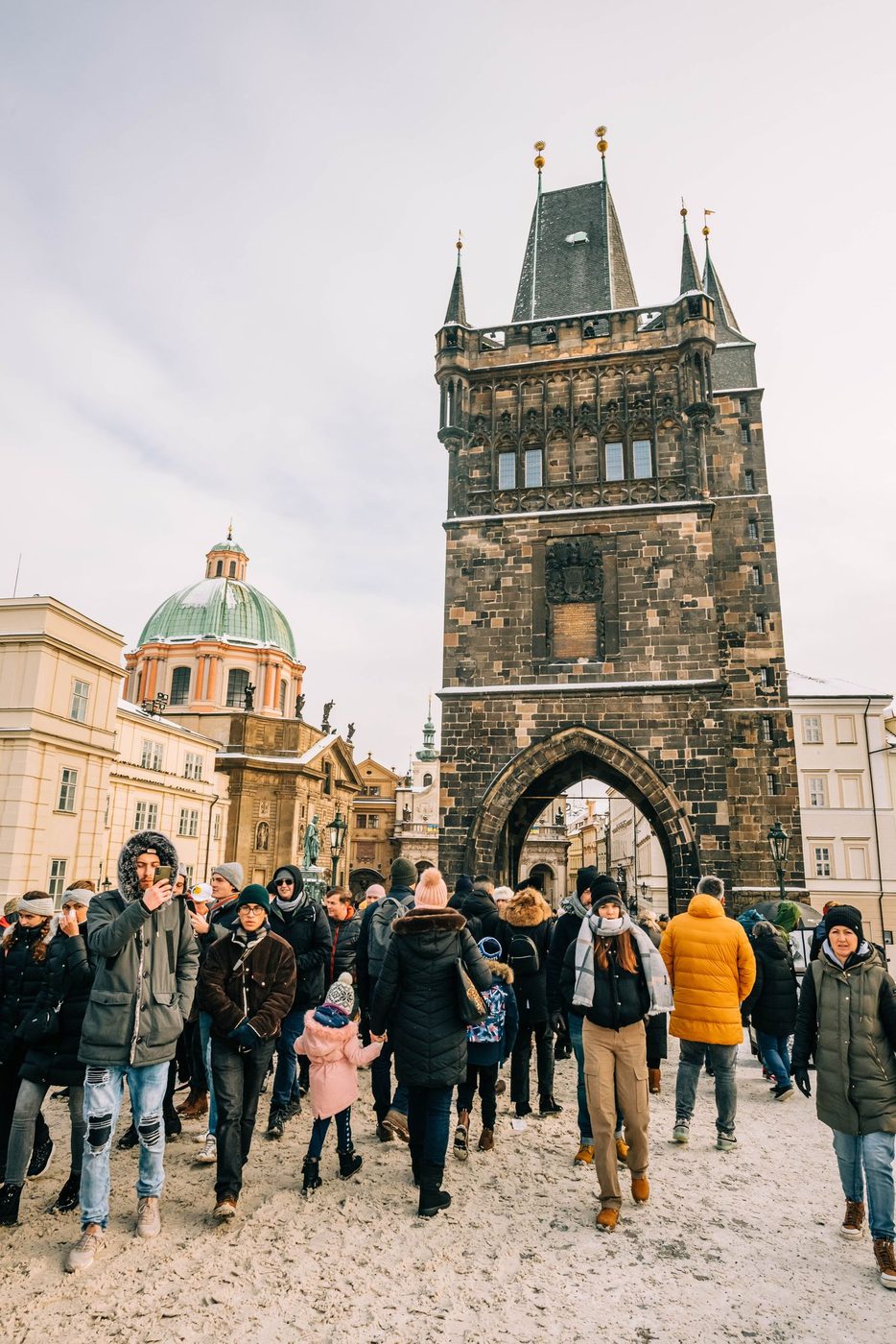 Exact Old Town Bridge Tower and its large pointed gateway are visibly framed with people at the approach.