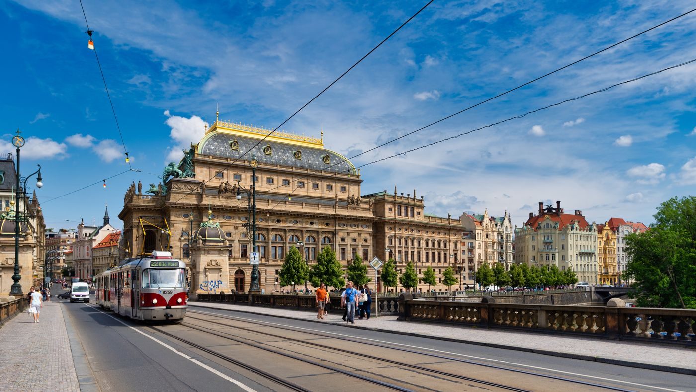 Exact Prague National Theatre and tram are visibly shown in daylight.