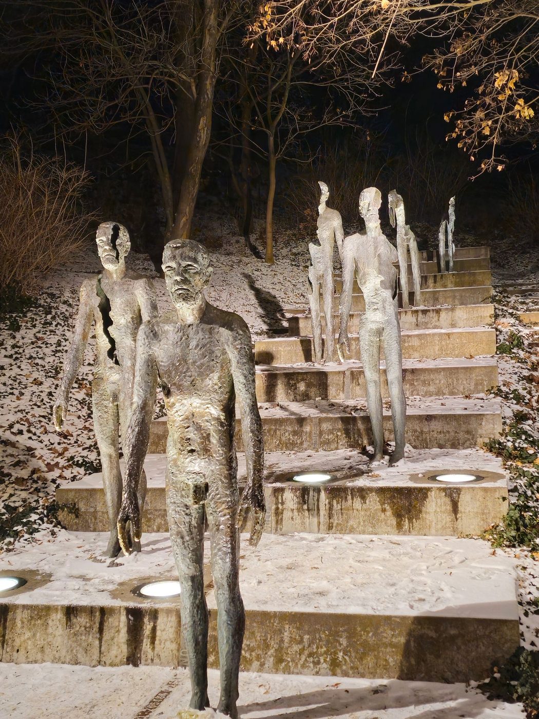 Pexels explicitly identifies the Memorial to the Victims of Communism in Prague; multiple bronze figures visibly stand in sequence on the staircase with different degrees of bodily completeness.