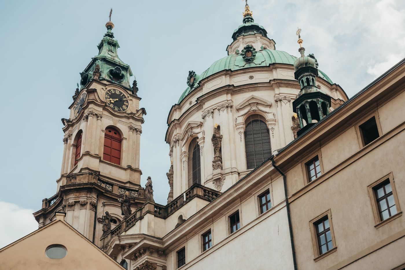 Wide Lesser Town view visibly places the separate dark clocked bell tower beside the large green St Nicholas dome.
