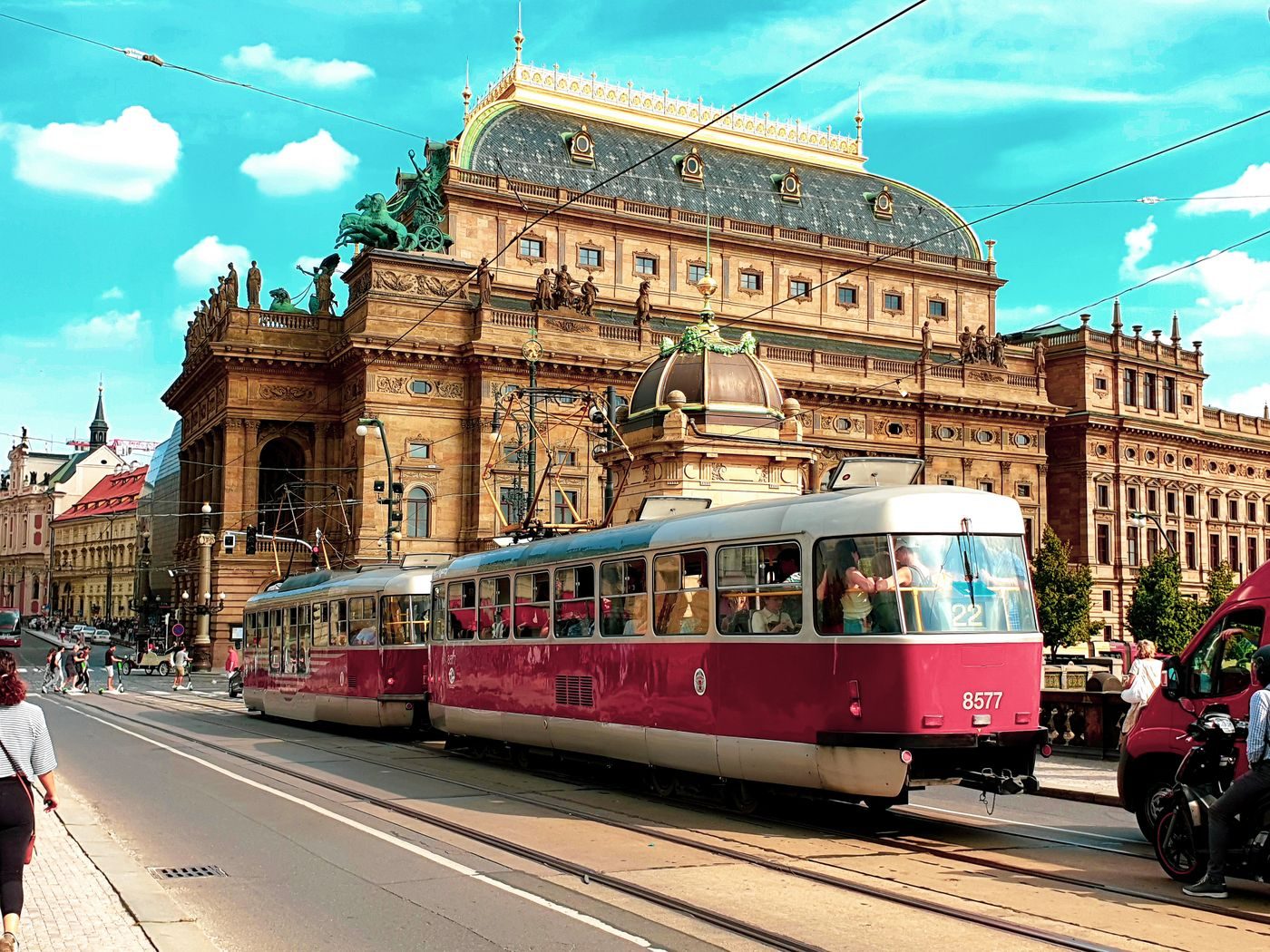 Red tram visibly passes Prague’s historic National Theatre.