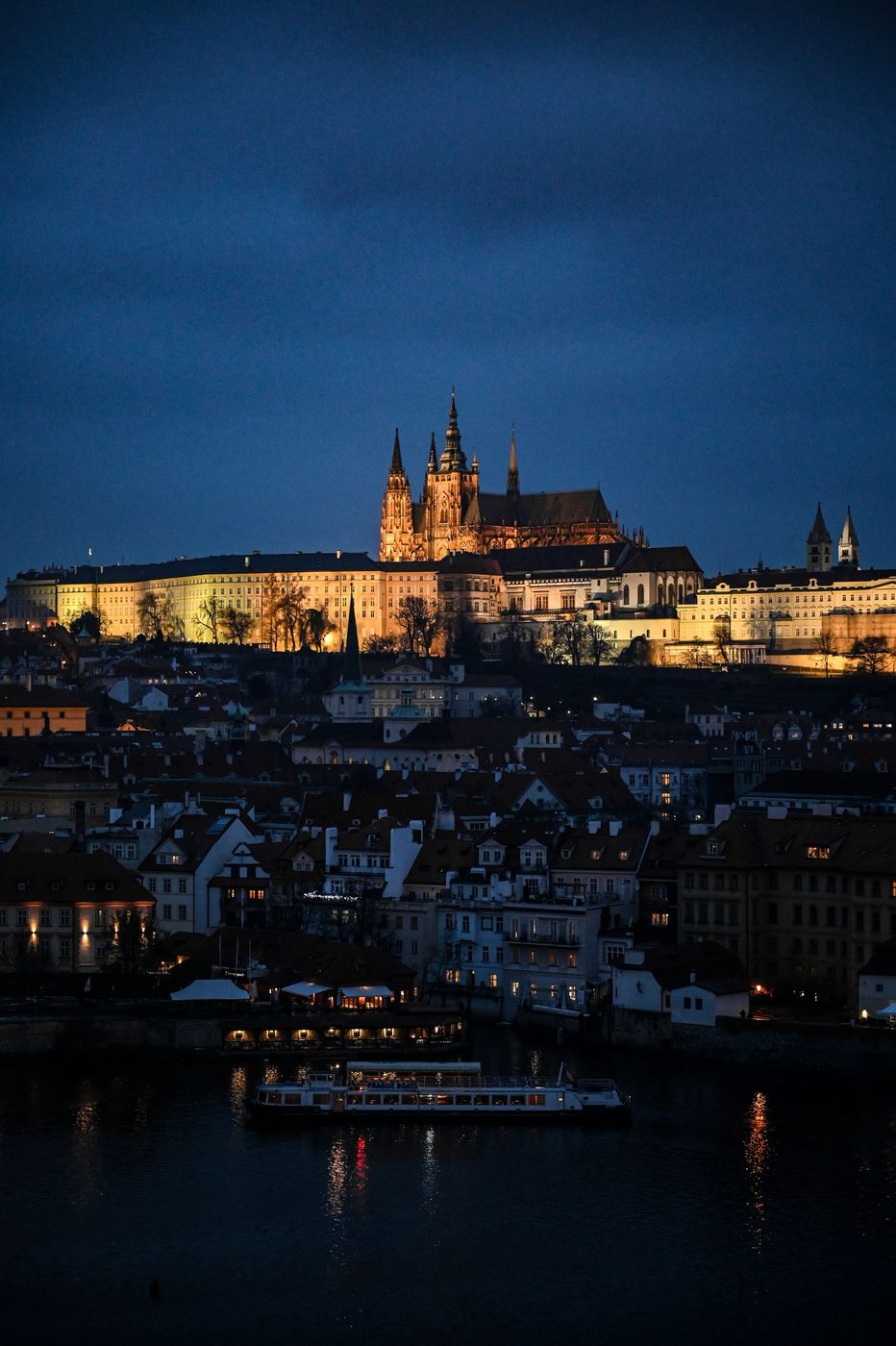 Prague Castle/Hradčany is visibly monumental over the city at dusk.