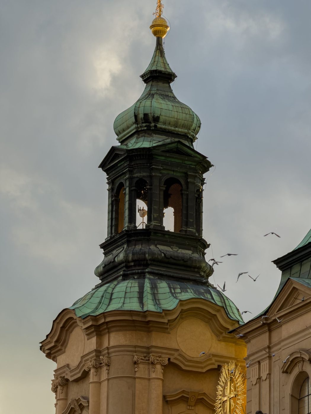 Tight vertical photograph isolates the St Nicholas bell tower with clock face and cupola.