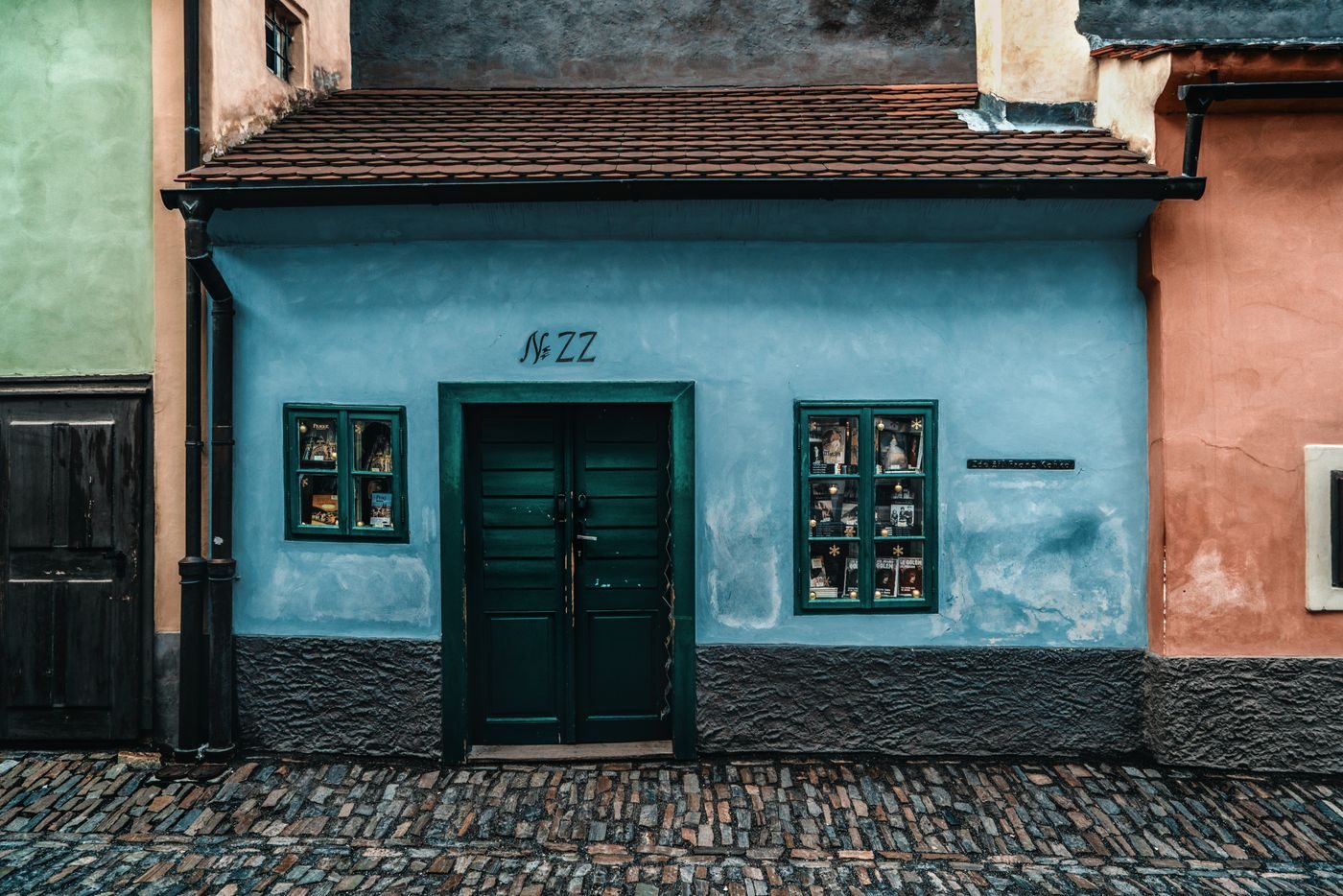 Exact Golden Lane close frame visibly shows a very small blue house façade and cobbled path.
