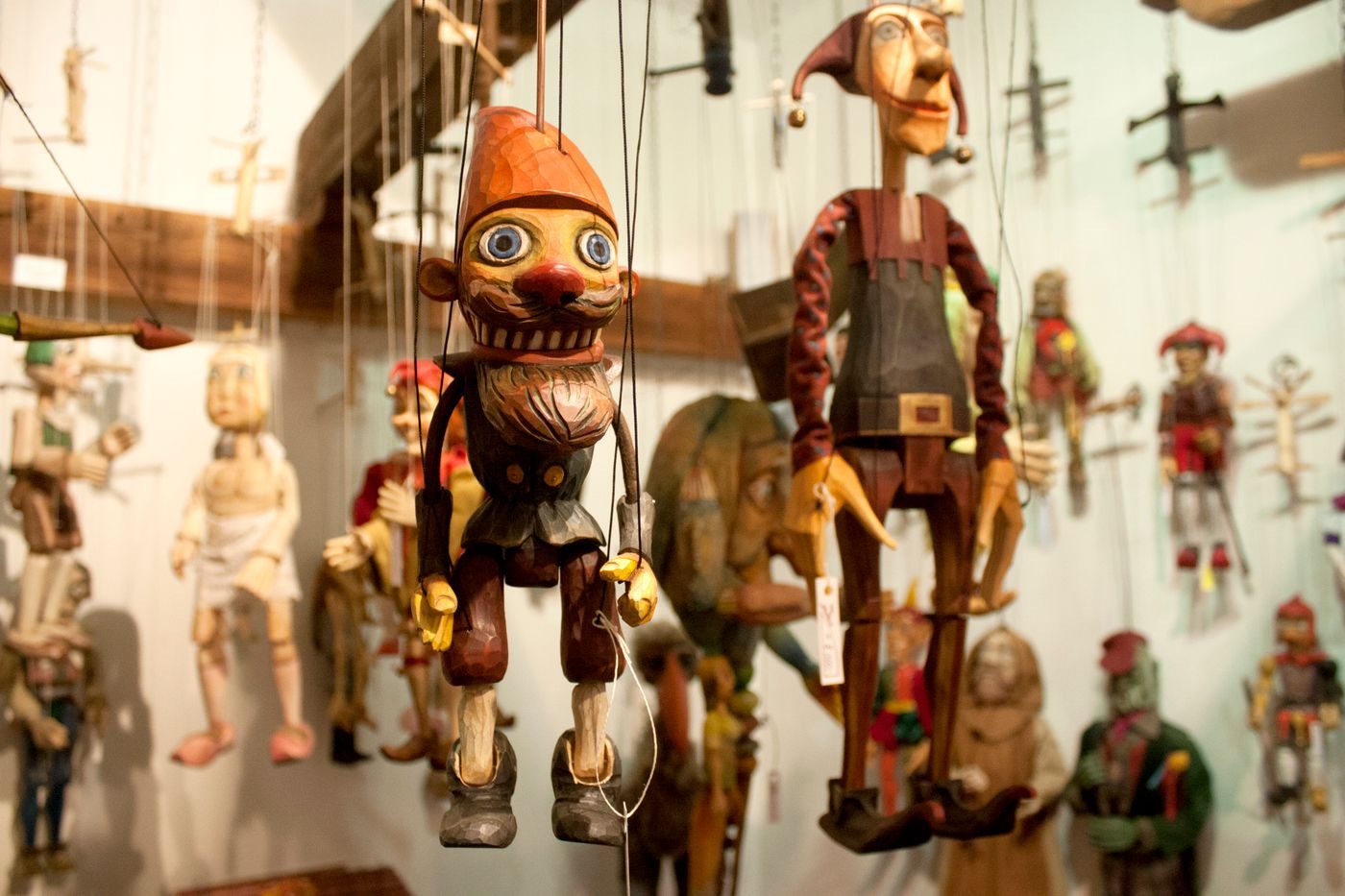 Multiple handcrafted wooden marionettes with visible strings and painted faces are shown close-up.